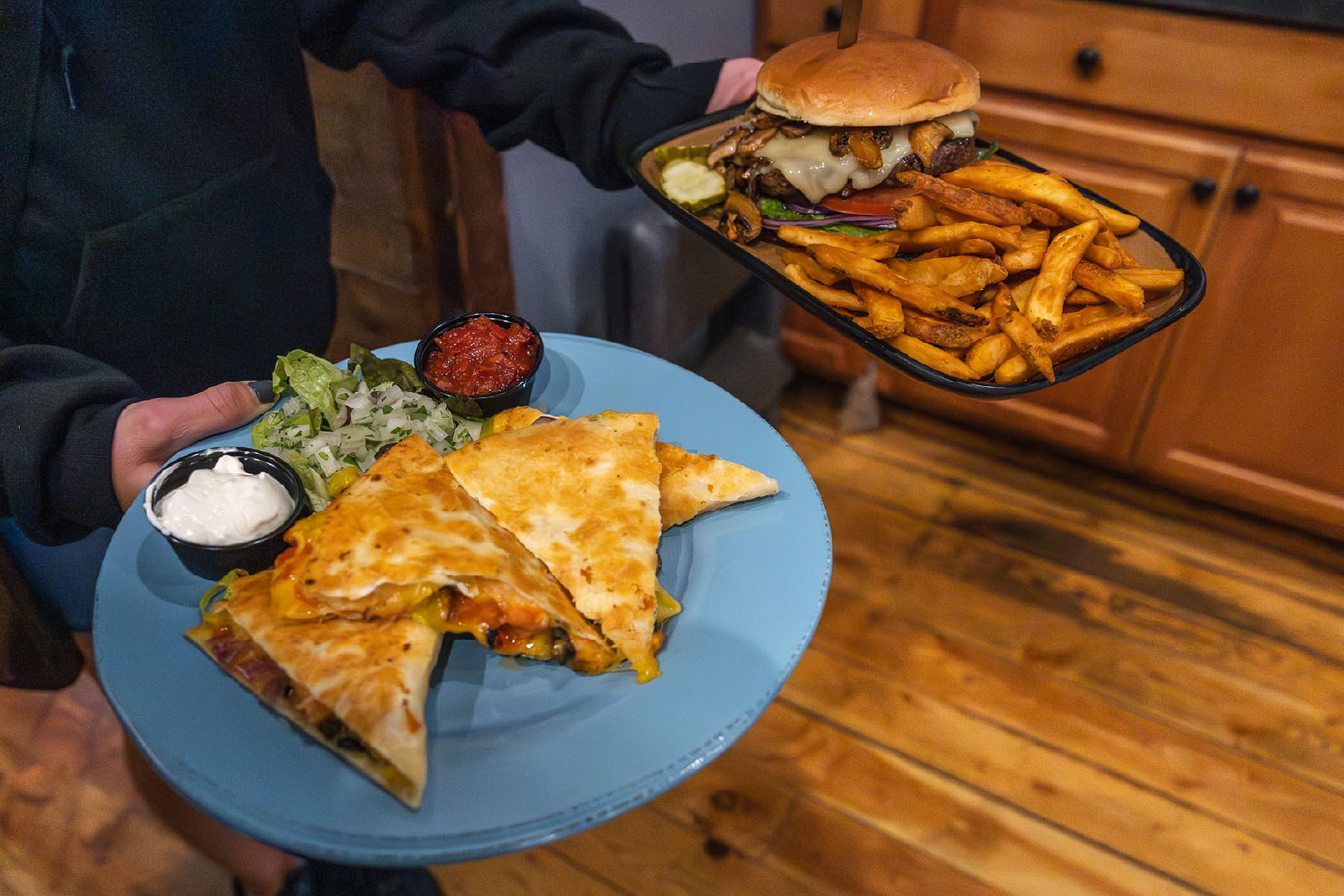 A quesadilla on a plate and a try with a burger and fries