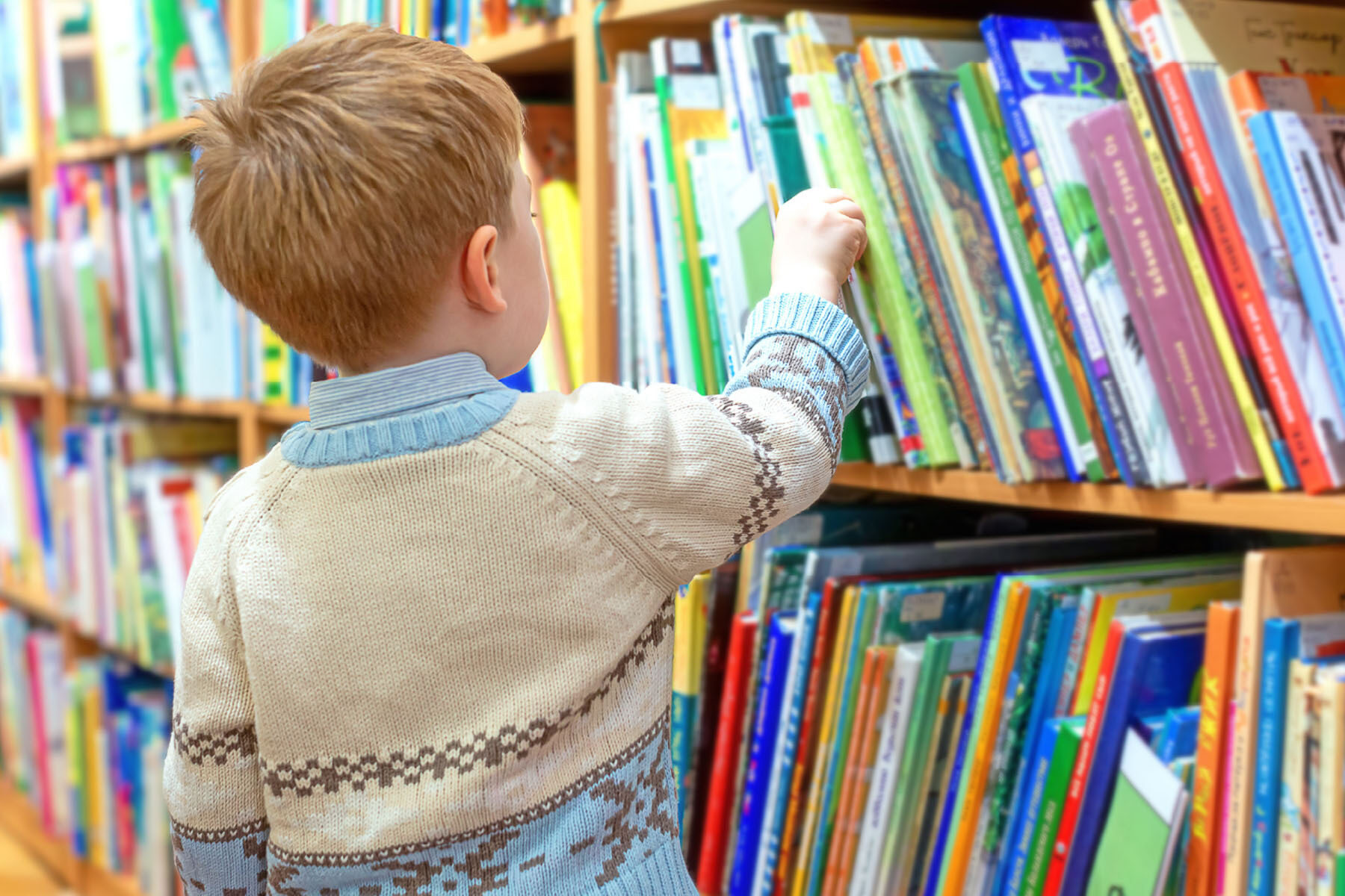 A young boy picking out books at a library